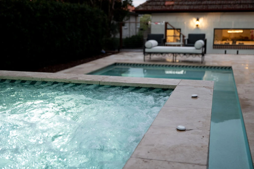 Aerial view of a custom concrete pool with glass fencing and paved surrounds