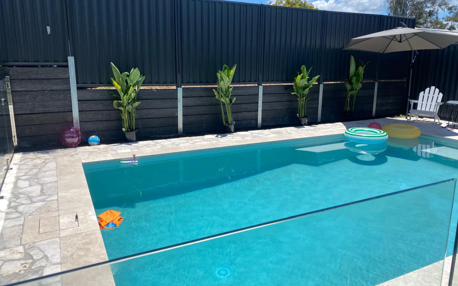 Poolside lifestyle with travertine coping, planting and umbrella